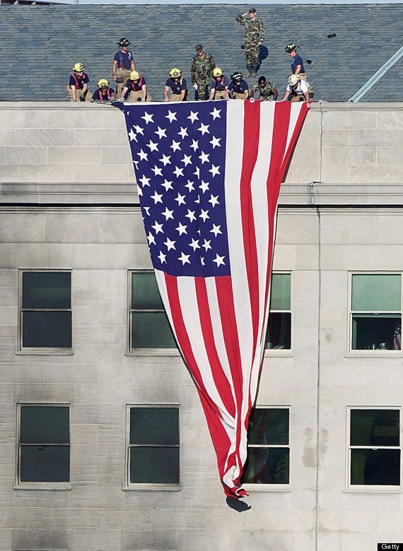 Firefighters and soldiers unfurl an Amer